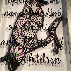 Può includere: Un ritaglio di carta nero e bianco di un corvo con un design a mandala viola e bianco. Il corvo è appollaiato su un ramo. Il testo "Mother is the name for God on the lips and the hearts of all children" è scritto in nero su sfondo bianco.