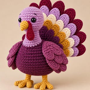 May include: A crocheted turkey toy featuring a light purple head, a dark purple body, and yellow feet. The turkey has a red wattle, a yellow beak, and black eyes. Its tail feathers are arranged in a fan shape with alternating layers of dark purple, light purple, cream, and mustard yellow yarn.
