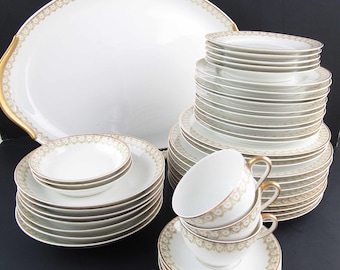 May include: A set of white porcelain dinnerware with a gold trim and a delicate floral pattern. The set includes plates, bowls, cups, and saucers.