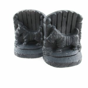May include: A pair of black bookends featuring a Scottish Terrier dog standing by a fence. The bookends are made of a smooth, black material and have a detailed design.