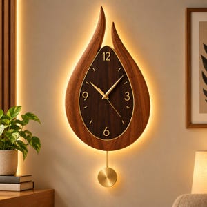 Puede incluir: Un reloj de pared con forma de gota de agua hecho de madera oscura con retroiluminación LED cálida integrada. La esfera tiene un centro marrón oscuro, números dorados en el 3, 6, 9 y 12, manecillas doradas y un péndulo dorado colgando.