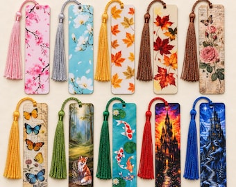 May include: Ten rectangular bookmarks with tassels, featuring diverse designs including cherry blossoms, autumn leaves, roses, butterflies, a fox in a forest, koi fish, a castle at sunset, and a snowy castle. Text reads: 10 Motive zur Auswahl.