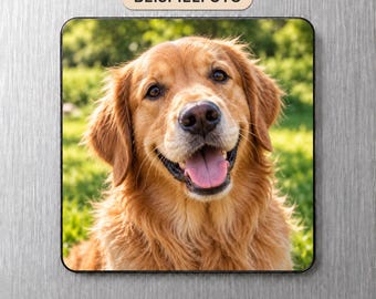 May include: A square magnet featuring a golden retriever with long, light brown fur, dark eyes, and a black nose. The dog has an open mouth with a visible pink tongue, set against a blurred green outdoor background. The text BEISPIELFOTO is visible.