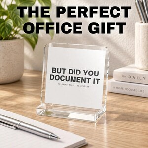 May include: A clear acrylic sign holder containing a white card with the black printed text BUT DID YOU DOCUMENT IT and the smaller text no paper trail, no problem. The sign is rectangular with a thick base and stands on a wooden surface.