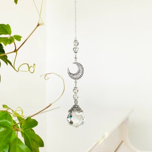 Può includere: Un acchiappasole di cristallo con una mezzaluna d'argento e una sfera di cristallo sfaccettata appesa a una catena d'argento.