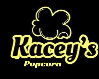 Może przedstawiać: Żółte logo na czarnym tle z tekstem "Kacey's Popcorn". Logo przedstawia stylizowany ziarenko popcornu.