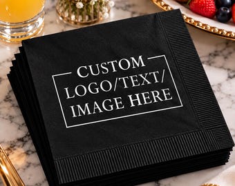 May include: A stack of square black paper napkins featuring a white rectangular border and the centered white text CUSTOM LOGO/TEXT/IMAGE HERE. The napkins have a textured, embossed border along the edges and a smooth center surface.