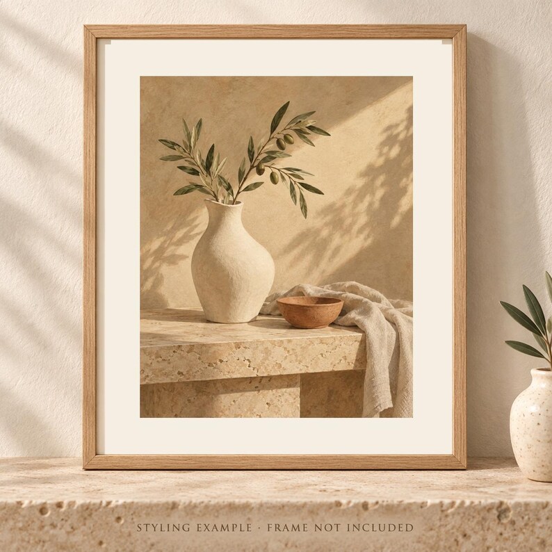 May include: A framed wall art print featuring a textured off-white vase holding olive branches with green leaves and small olives. Next to the vase sits a small terracotta-colored bowl and a draped beige fabric cloth on a stone surface.