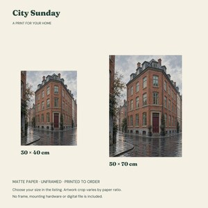 May include: City Sunday print for your home featuring a red brick corner building on a wet street. Two size options are displayed: 30 x 40 cm and 50 x 70 cm. The artwork is printed on matte paper, is unframed, and is printed to order.