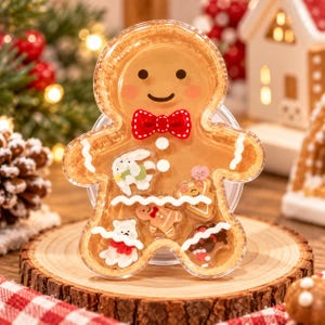 May include: A clear plastic gingerbread man-shaped container filled with small decorative holiday-themed charms. The container features a red and white polka dot bow tie, white icing details, and a smiling face with rosy cheeks printed on the front.