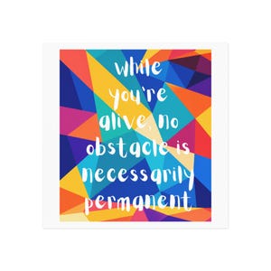 May include: A square wall art print featuring a vibrant, multi-coloured geometric pattern of triangles in shades of blue, yellow, orange, red, and purple. Centered in white, hand-lettered text is the quote: while you're alive, no obstacle is necessarily permanent.