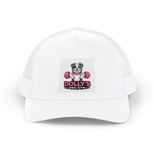 May include: A white trucker cap featuring a graphic of a dog with a green bow lifting a pink barbell. Below the dog, the text reads DOLLY'S DOG GYM in pink and black lettering. The cap has a solid front panel and a mesh back for ventilation.