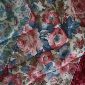 May include: A patchwork quilt featuring a variety of floral patterns in shades of pink, blue, and white. The quilt is made from different fabrics and textures, creating a unique and interesting design.