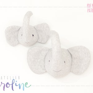 Peut inclure: Deux décorations murales en forme de tête d'éléphant en feutre gris. Les éléphants ont des yeux et un sourire brodés. Le texte "PDF PATTERN PATRON PDF" est dans le coin supérieur droit de l'image.