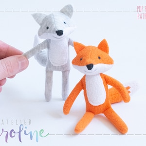 Op de afbeelding: Twee pluche vossen, een grijze en een oranje, met witte accenten. De grijze vos houdt de poot van de oranje vos vast. De tekst "PDF PATTERN PATRON PDF" staat in de rechterbovenhoek van de afbeelding.
