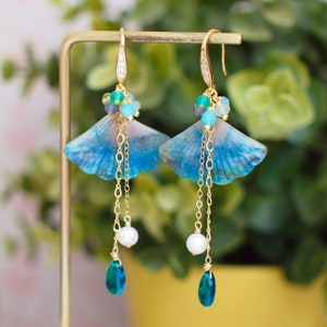 May include: A pair of blue and white ginkgo leaf earrings with gold chains, pearls, and blue gemstone drops.