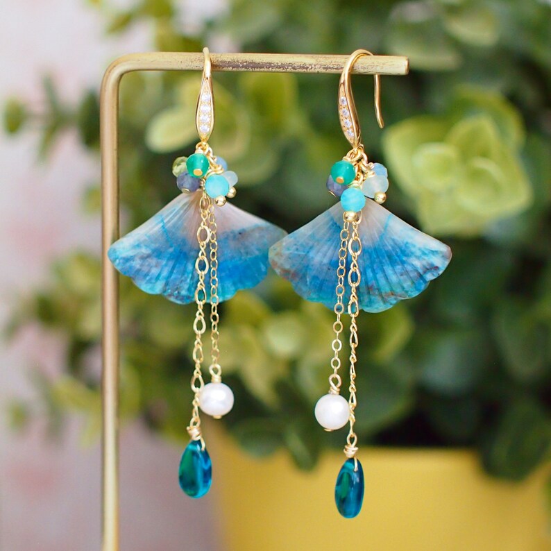 May include: A pair of blue and white ginkgo leaf earrings with gold chains, pearls, and blue gemstone drops.