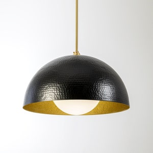 May include: A black hammered metal pendant light with a gold interior and a white globe light bulb.