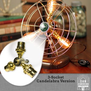 May include: A vintage-style fan lamp kit with a bronze finish and a wire cage. The lamp features three Edison-style bulbs and a 3-socket candelabra version. The text "Fan Lamp Kit" is at the top.