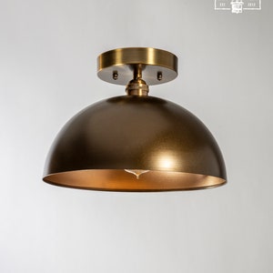 May include: A brass dome ceiling light fixture with a gold interior. The light fixture is mounted on a white ceiling.