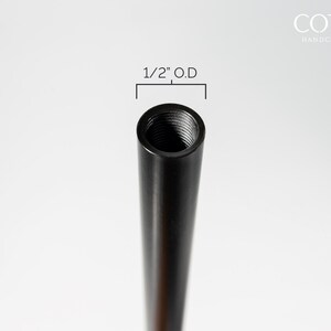 May include: Close-up of a black metal pipe with a 1/2" outer diameter and 1/8 ips thread. The pipe is threaded on one end.