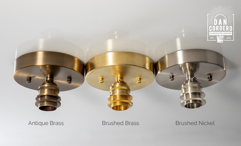 May include: Three ceiling light fixtures with white glass shades and different finishes: antique brass, brushed brass, and brushed nickel. Each fixture has a standard light bulb socket.