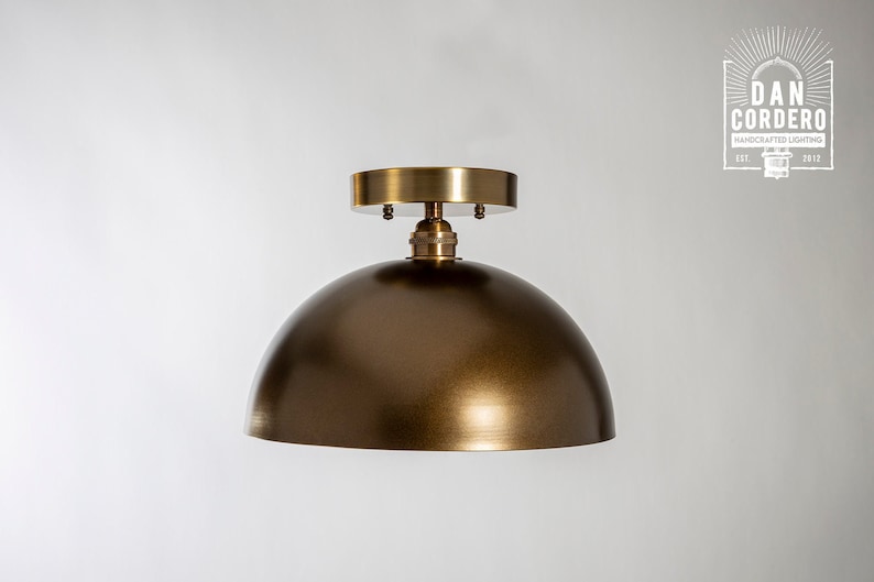 May include: A gold-toned dome-shaped ceiling light fixture with a simple design.