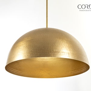 May include: A gold hammered metal dome pendant light fixture.  CORDERO HANDCRAFTED LIGHTING is printed in black text on a white background.