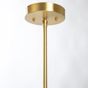 May include: A gold metal ceiling mount for a pendant light fixture. The mount has three screw holes and a round, flat base.