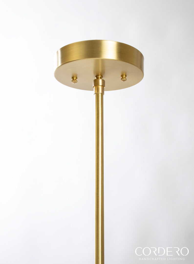 May include: A gold metal ceiling mount for a pendant light fixture. The mount has three screw holes and a round, flat base.