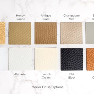 May include: Interior finish options for furniture, shown as swatches of different colors and textures.  The options include Gold, Honey Blonde, Antique Brass, Champagne Mist, Satin Pebble, Satin White, Alabaster, French Cream, Flat Black, and Aged Copper.