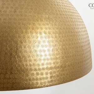 May include: A gold-toned, round, hammered metal lampshade with a textured surface.