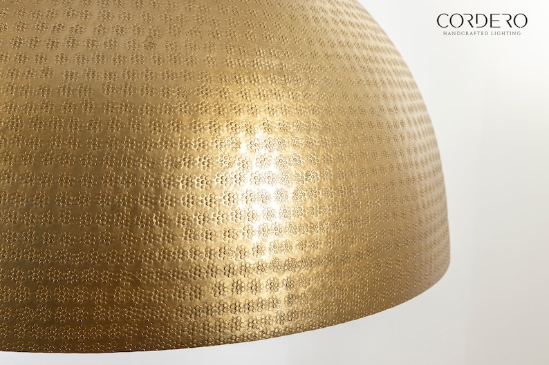 May include: A gold-toned, round, hammered metal lampshade with a textured surface.