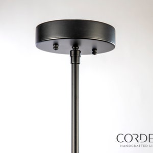 May include: Black metal ceiling mount for a pendant light fixture. The mount has a round canopy and a threaded rod.