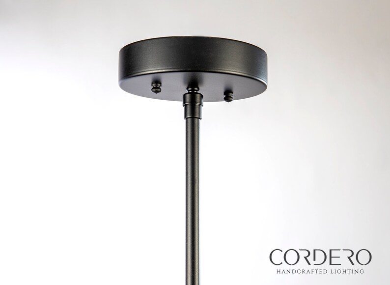 May include: Black metal ceiling mount for a pendant light fixture. The mount has a round canopy and a threaded rod.