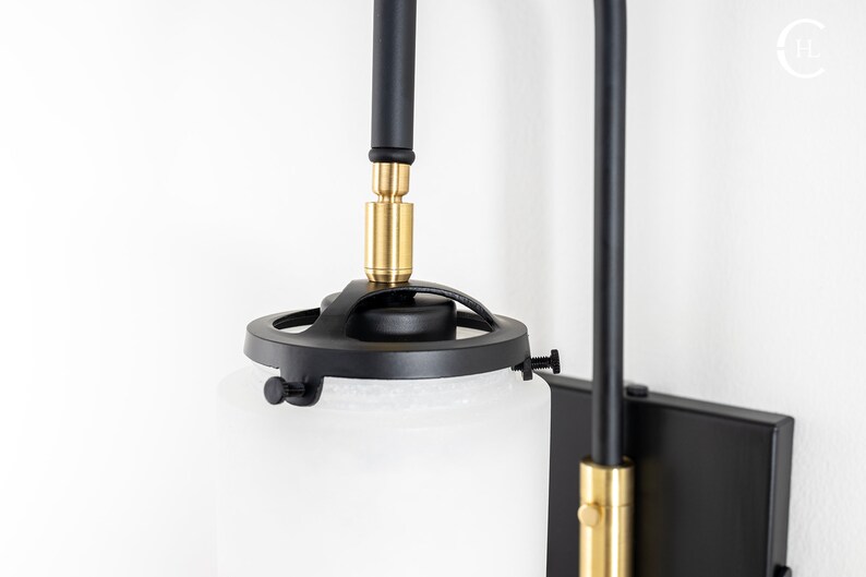 May include: Black and gold wall sconce with a frosted glass shade. The sconce has a swivel arm and a round base.