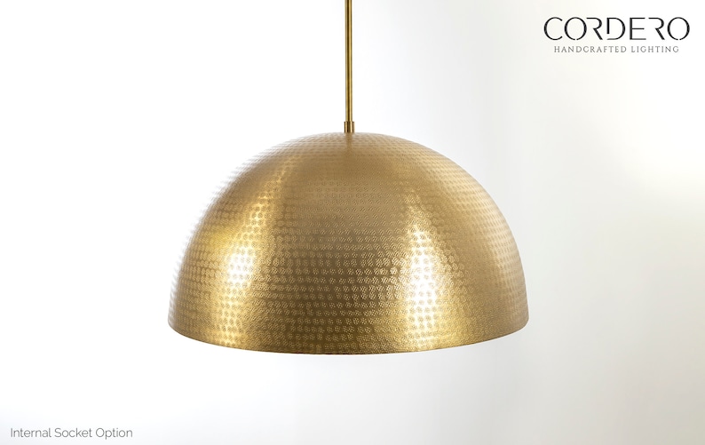 May include: A gold, hammered metal pendant light fixture with a dome-shaped shade. The shade has a textured surface with a pattern of small circles.