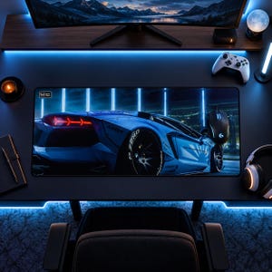 Pode incluir: Um tapete de secretária retangular com uma impressão de alta resolução de um carro desportivo azul com luzes traseiras vermelhas e rodas pretas. O tapete tem um pequeno logótipo no canto superior esquerdo sobre uma secretária escura.
