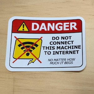 May include: A rectangular sticker with a red header containing the word DANGER and a yellow warning triangle. The white body features a yellow Wi-Fi icon crossed out with a red X, and the text DO NOT CONNECT THIS MACHINE TO INTERNET NO MATTER HOW MUCH IT BEGS.