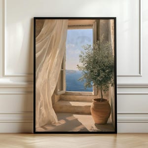 May include: A framed wall art print depicting an open window overlooking a blue sea. A sheer beige curtain hangs to the left, while a green olive tree in a terracotta pot sits on the right side of the stone ledge under a bright sky.