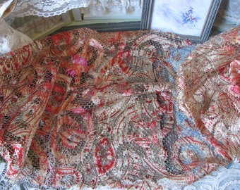 Pode incluir: Um tecido de renda vintage com um padrão paisley vermelho e branco. O tecido é delicado e tem um aspecto desgastado.