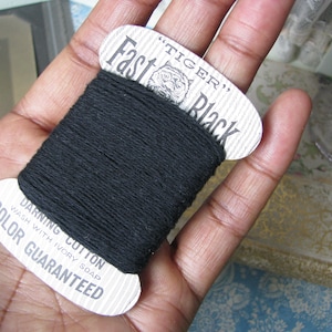May include: A spool of black darning cotton with a white label that reads "Tiger" "Fast Black" and "Darning Cotton Wash with Ivory Soap Color Guaranteed".