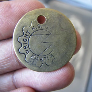 Peut inclure: Un porte-clés en laiton avec un motif d'engrenage et le texte "WILBUR WRIGHT H.S. IL" gravé dessus.