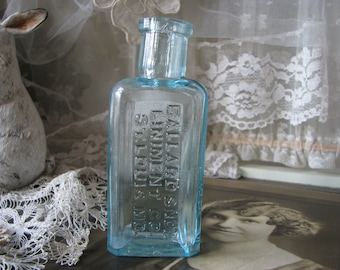 Puede incluir: Una botella de vidrio azul vintage con una etiqueta que dice "Ballard Snow Liniment Co. St. Louis, Mo."