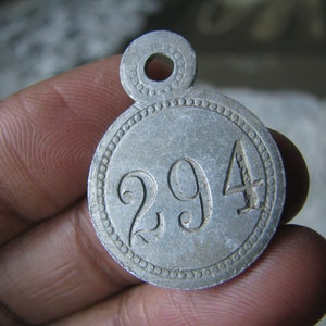 May include: A silver metal tag with a hole at the top and the number 294 embossed on the front.