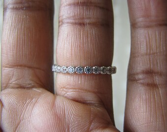 Puede incluir: Un anillo de banda de plata con una fila de pequeñas piedras de circonita cúbica transparentes.