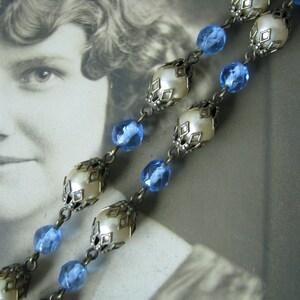 May include: A vintage necklace with blue glass beads and white pearl-like beads in ornate metal settings.