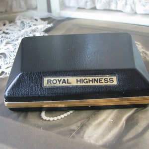 May include: A black rectangular box with a gold trim and the words "ROYAL HIGHNESS" printed on the top.