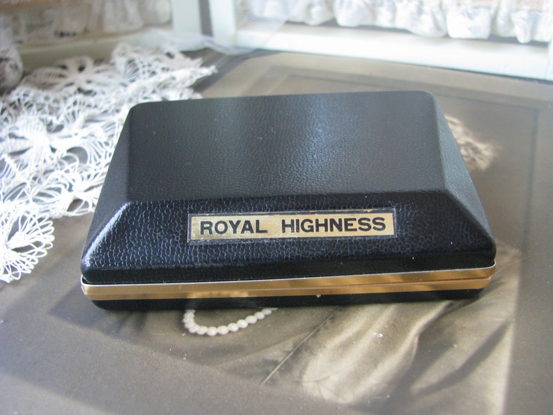 May include: A black rectangular box with a gold trim and the words "ROYAL HIGHNESS" printed on the top.