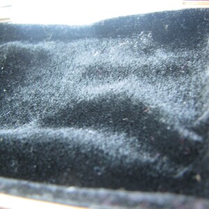 May include: A black velvet-lined box with a gold trim.